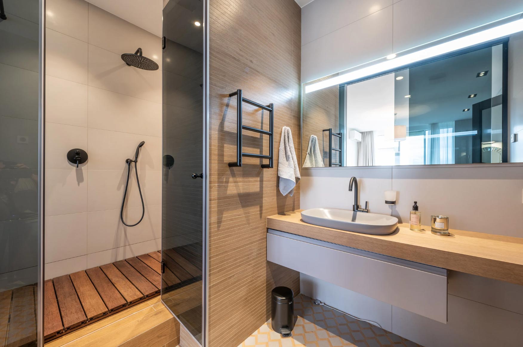 bathroom-img-2 Discover the elegance of residential remodeling in this modern bathroom located in Rockville. Featuring a sleek glass shower, wooden floor, wall-mounted sink, towel rack, and a large mirror, it represents the epitome of style and functionality for any MD home.